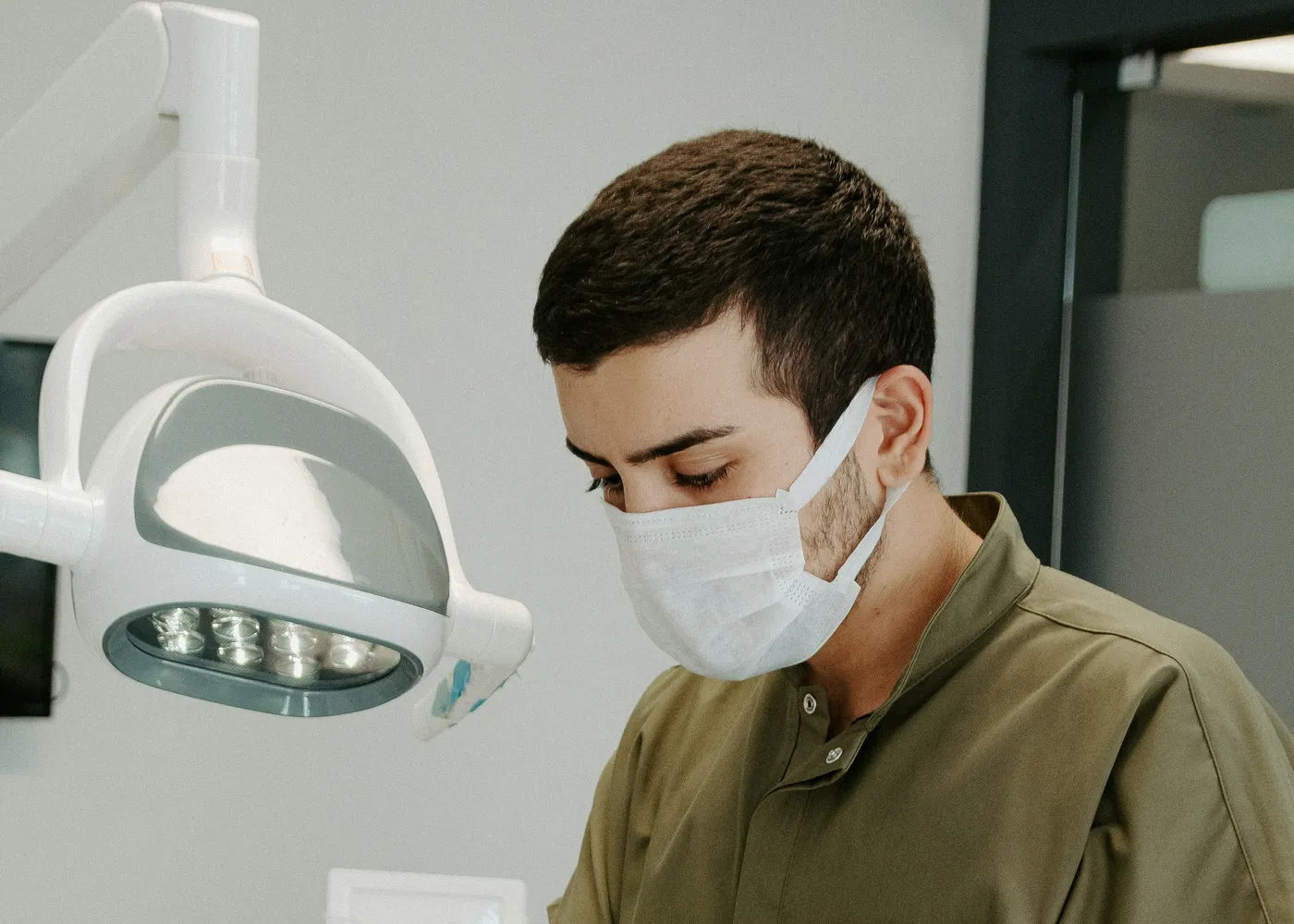 Odontólogo con mascarilla bajo la lámpara de la consulta